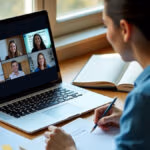 Ein Student nimmt in einem sonnendurchfluteten Homeoffice mit ordentlich arrangierten Studienmaterialien und Kulturtheorie-Lehrbüchern an einer Videokonferenz für Kulturwissenschaften teil.
